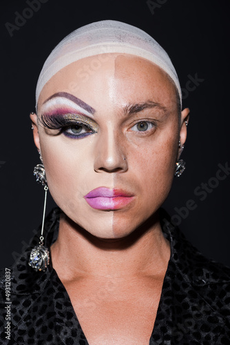 Obraz na płótnie portrait of man with earrings and spectacular makeup on half face isolated on black