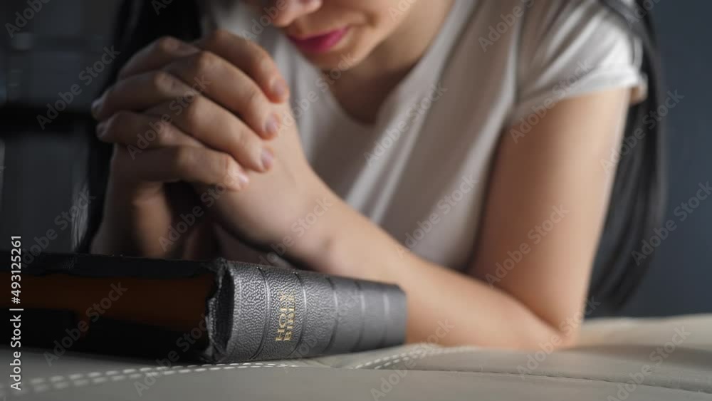 girl praying indoors at bedtime lifestyle on bible. religion concept evening prayer woman brunette hands on bible praying by bed girl praying indoors at bedtime lifestyle on bible. religion concept evening prayer woman brunette hands on bible praying by bed