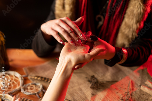 The witch makes divination on hand. The seer looks at the man's hand and sees his future.