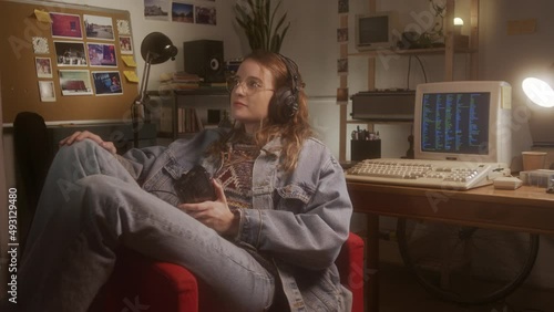 A girl listening to music and following the rhythm with a classic walkman player in her bedroom.