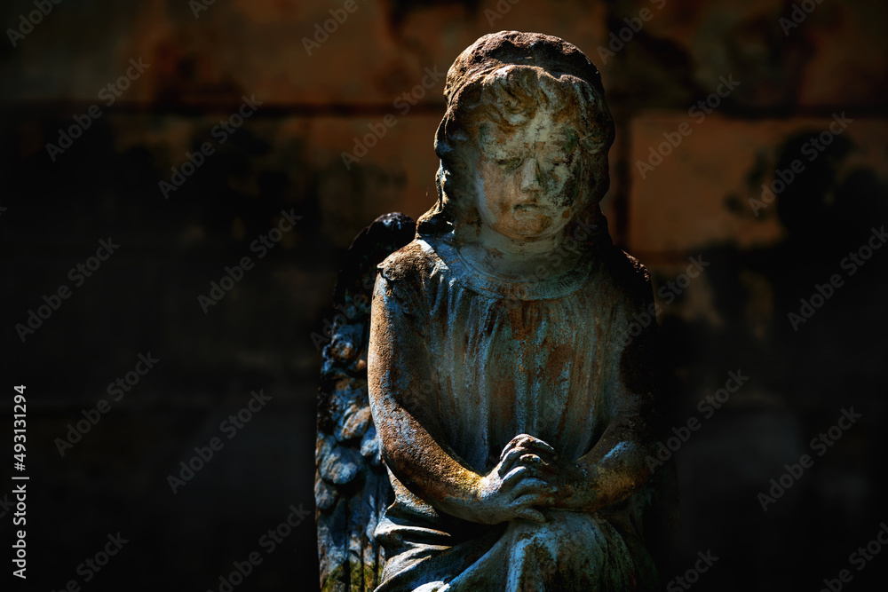 Praying angel. Fragment of a very ancient statue. Copy space.