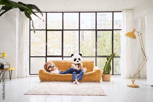 Two unrecognizable women with animal mask bear panda lying at sofa home - Beautiful living room indoors people disguised © CarlosBarquero