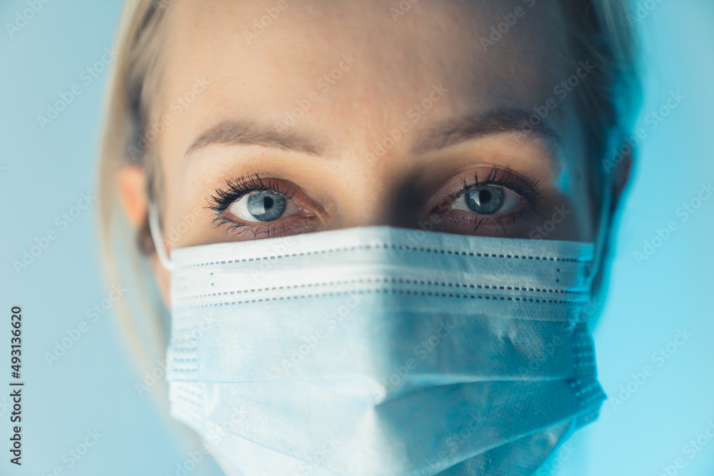 Tiredness in the eyes of European health worker. Close up studio shot caucasian woman wearing surgical mask. High quality photo Tiredness in the eyes of European health worker. Close up studio shot caucasian woman wearing surgical mask. High quality photo