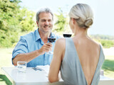 Enjoying a lunch date. Happy mature couple toasting their love with two glasses of wine while outdoors.