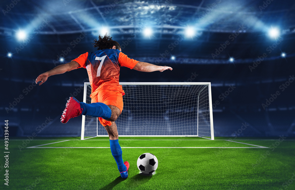 Soccer scene at night match with player in an orange and blue uniform kicking the penalty kick - obrazy, fototapety, plakaty 