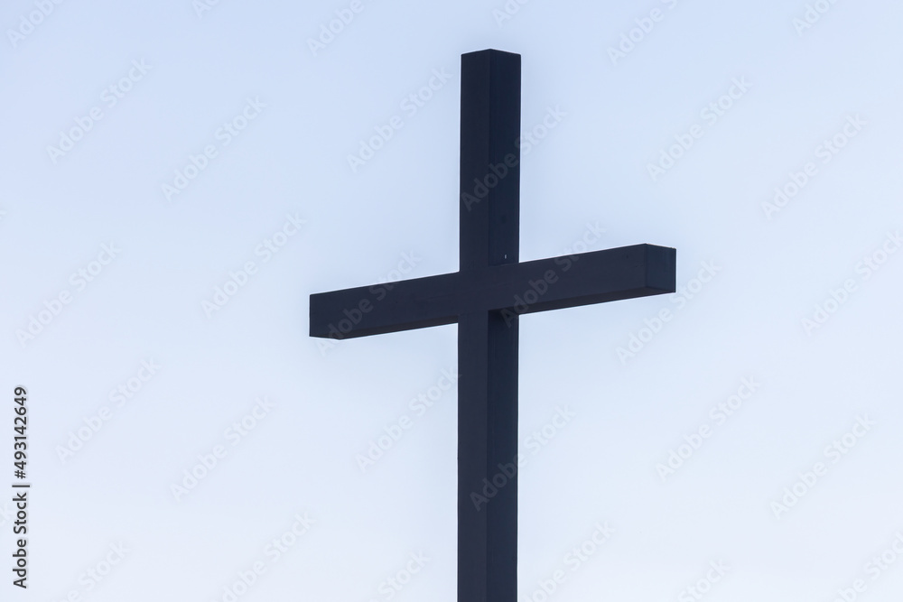 dark silhouetted cross on pale blue sky dark silhouetted cross on pale blue sky