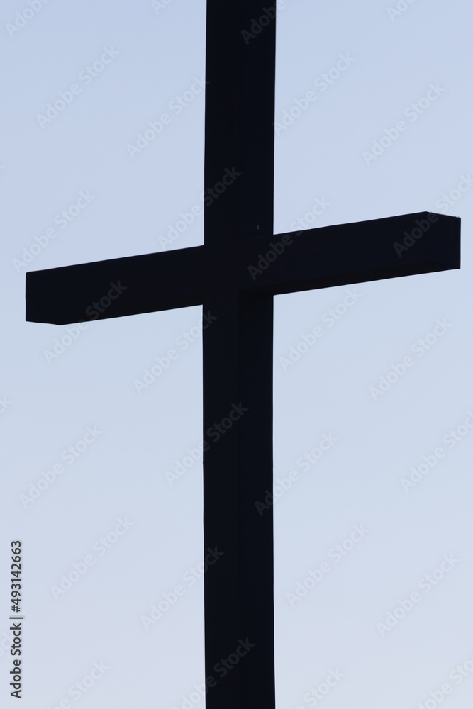 pale blue sky with dark silhouetted cross