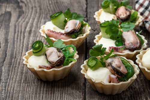 Mini tarts filled with marinated squid and mussels on wooden table