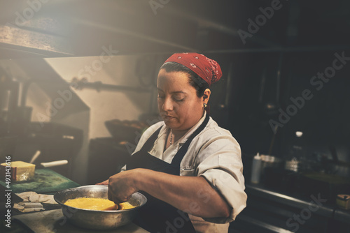 Theres some stirring going on in the kitchen. Shot of a focused chef preparing a dish in the kitchen of a restaurant.
