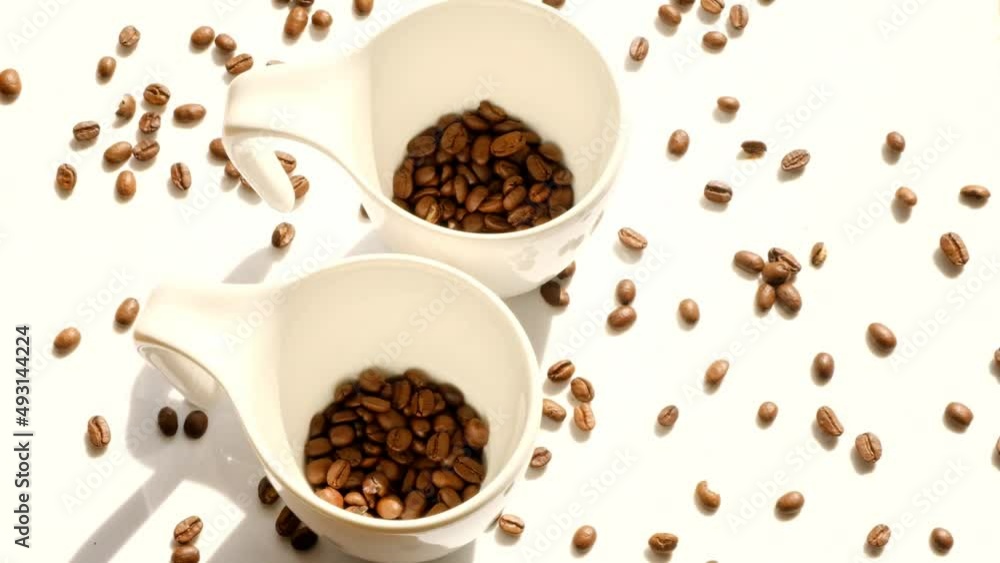Coffee in white cups. Coffee beans in white ceramic cups and falling coffee beans.Traditional morning drink. Coffee in white cups. Coffee beans in white ceramic cups and falling coffee beans.Traditional morning drink.