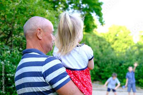 Fotografi close-up of small child, 2-year-old blonde girl in red dress, old man, grandfath