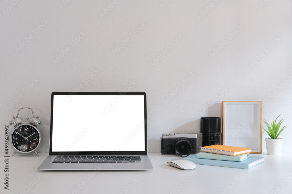 Computer laptop, camera, books and picture frame on white table. Computer laptop, camera, books and picture frame on white table.