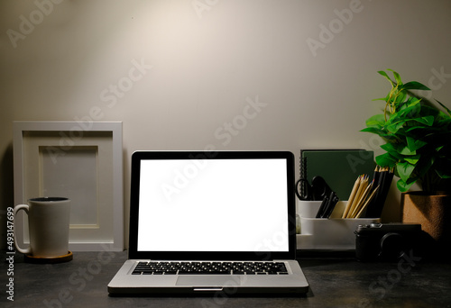 Laptop computer, picture frame, houseplant and coffee cup on black table. © wattana