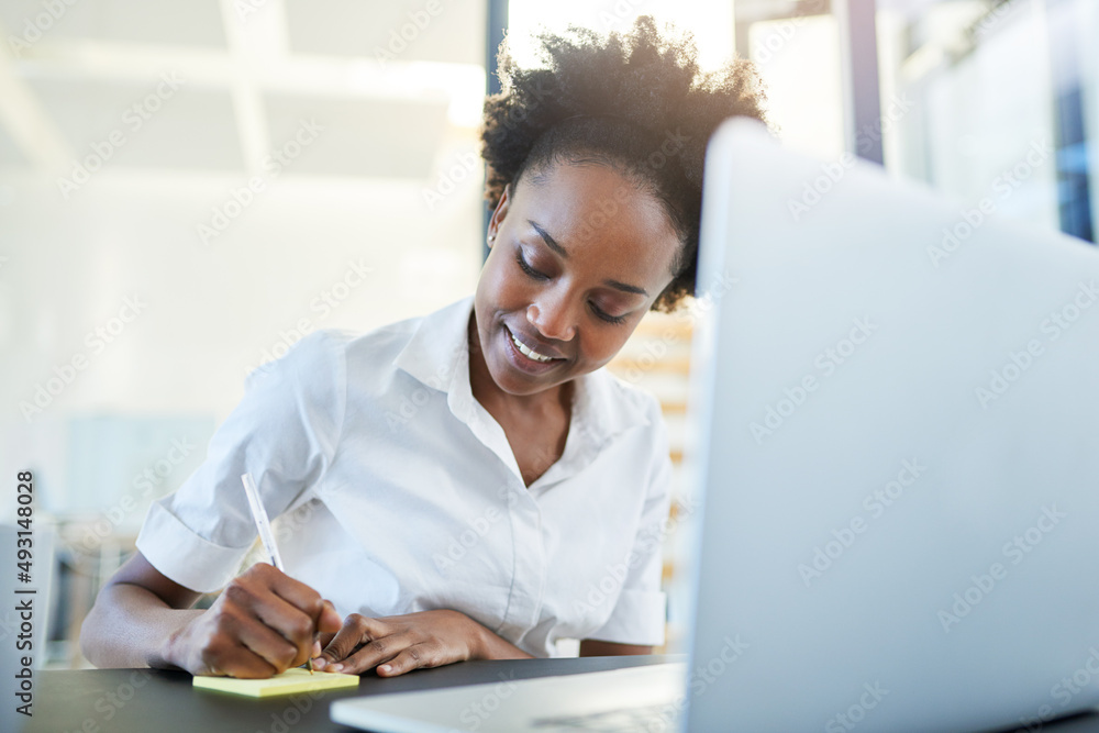Jotting down some innovative business ideas. Cropped shot of a young businesswoman writing notes while working on a laptop in a modern office. Jotting down some innovative business ideas. Cropped shot of a young businesswoman writing notes while working on a laptop in a modern office.
