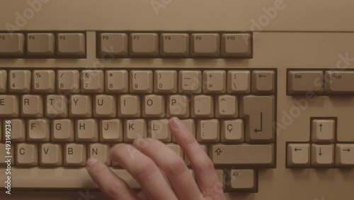 Hands typing on the keyboard of an old micro computer. Aerial view.
