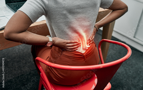 Pay attention to your posture to prevent pain. Closeup shot of an unrecognisable businesswoman suffering with back pain while working in an office. photo