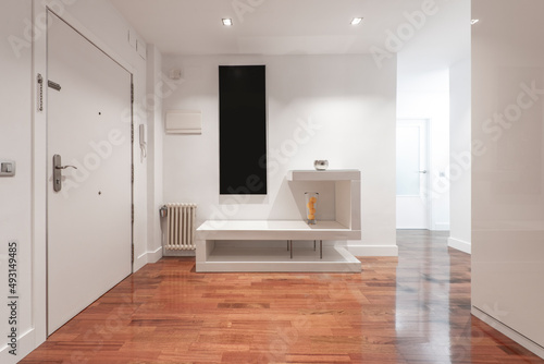 Entrance hall of a house with light modern decoration with mahogany oak parquet flooring and white front door