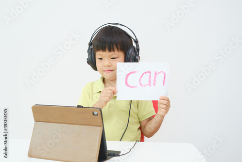 Little Asian child using tablet pc studying online lesson at home, Kid learn to read via e-learning , English lesson, Kindergarten closed during Covid-19 health crisis, Distance learning concept