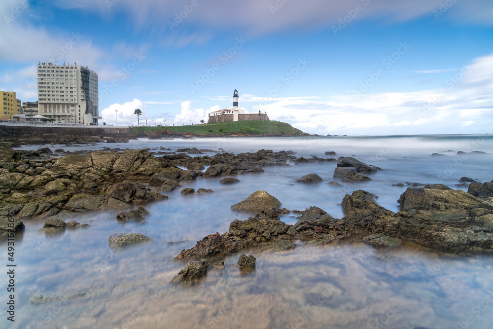 Fototapeta premium The historic architecture of Salvador in Bahia, Brazil showcasing the Farol da Barra Lighthouse at Bahia de Todos os Santos Bay on a sunny summer day