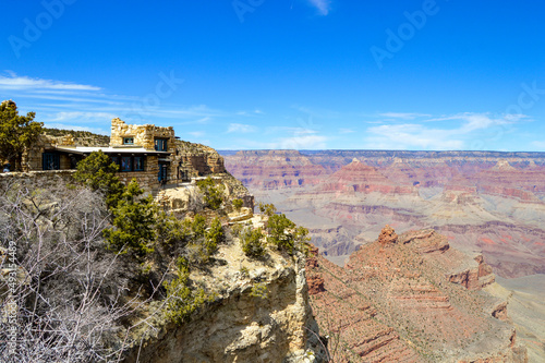 Lookout Studio sits on a cliffside overlooking the Grand Canyon in the National Park under blue skies with a few whispy white clouds.