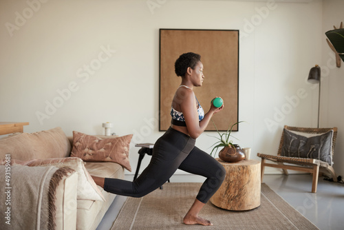 Be stronger than your excuses. Shot of a young woman exercising at home.