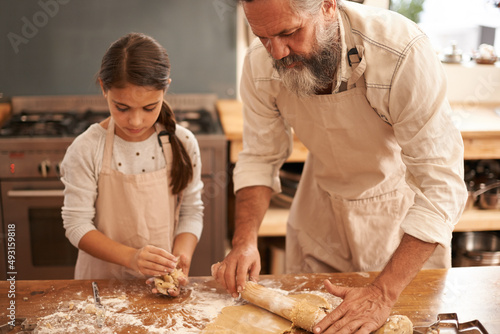 Theyre serious about baking. Shot of a girl and her grandfather baking together in the kitchen.