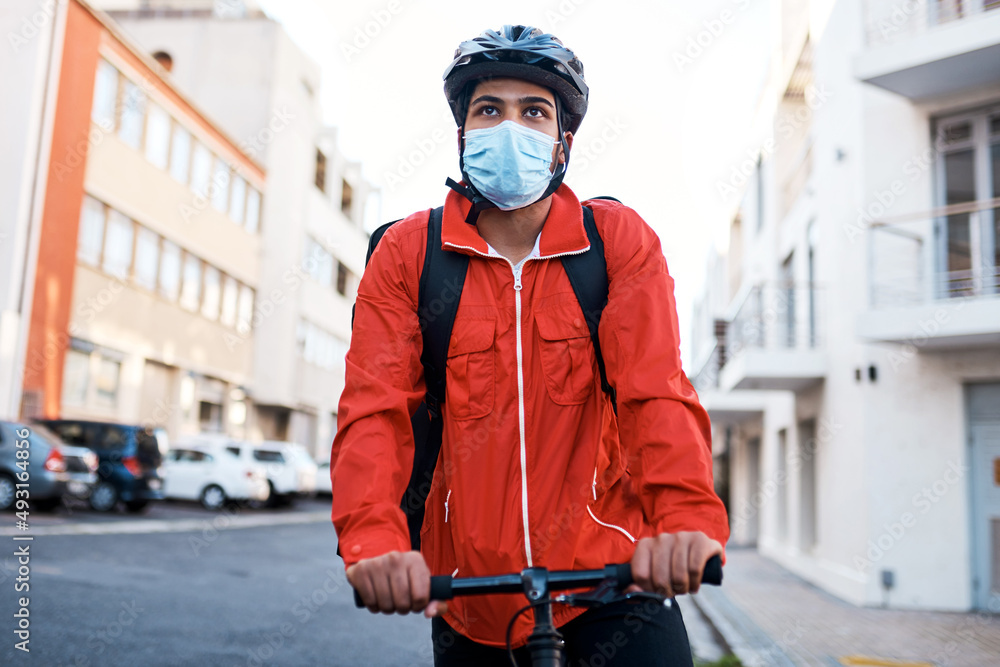 Masked and ready for his next delivery. Shot of a masked man out on his bicycle to do a delivery. Masked and ready for his next delivery. Shot of a masked man out on his bicycle to do a delivery.