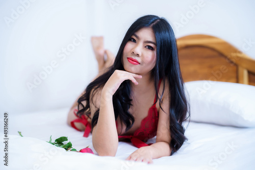Tanned woman's body,Thailand Asian sexy young woman model in sexy red lingerie holding a red rose posing on the bed in the bedroom ,valentine's day concept