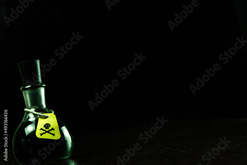 vial of poison with a hazard warning label, on a dark background, toning, short focus
