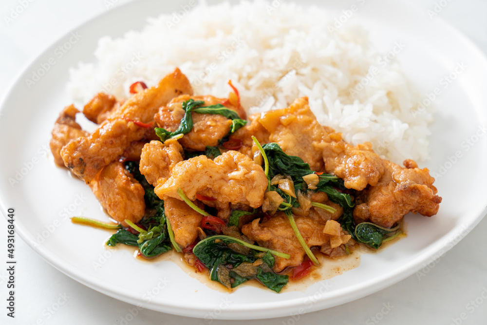 stir-fried fried fish with basil and chili in thai style topped on rice stir-fried fried fish with basil and chili in thai style topped on rice