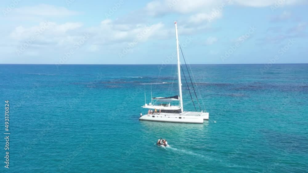 Tourists ferried to catamaran with inflatable boat, azure blue Caribbean Tourists ferried to catamaran with inflatable boat, azure blue Caribbean