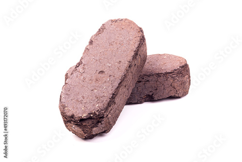 white background. the briquette is dark in color. an alternative type of fuel for heating. close-up. photo