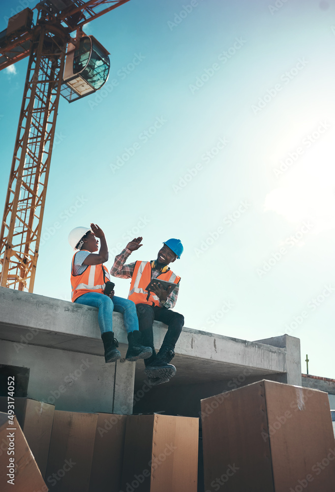When your office feels like a playground. Shot of a young man and woman sitting on top of a building at a construction site and giving each other a high five. When your office feels like a playground. Shot of a young man and woman sitting on top of a building at a construction site and giving each other a high five.