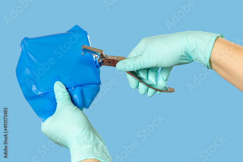 Dentist's hands in gloves with dental punch and cofferdam scarf. photo