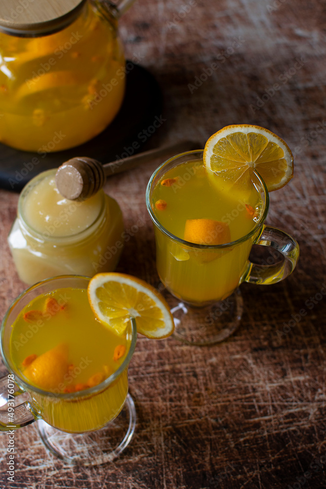 Two mugs with sea buckthorn tea on a wooden table. Top view, dark background, vertical orientation. Two mugs with sea buckthorn tea on a wooden table. Top view, dark background, vertical orientation.