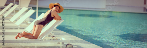 фотографія Young Asian woman with hat relaxing beside the pool at luxury hotel