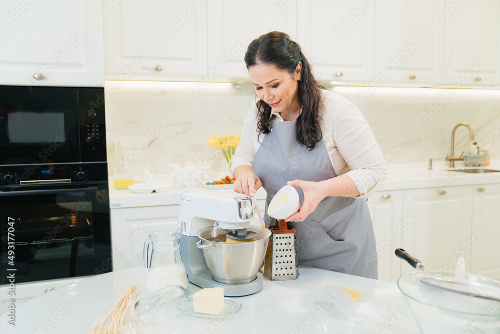 a woman cook adds citrus zest to the bowl of a mixer to make pastries or cream. a woman cook adds citrus zest to the bowl of a mixer to make pastries or cream.
