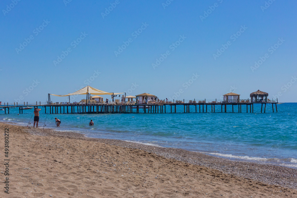 Pier and beach on a clear day with blue sea