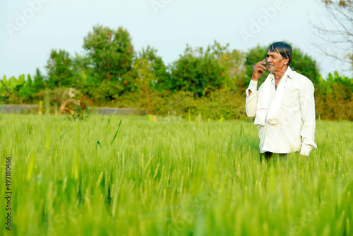 Indian farmer talking on smartphone at wheat field