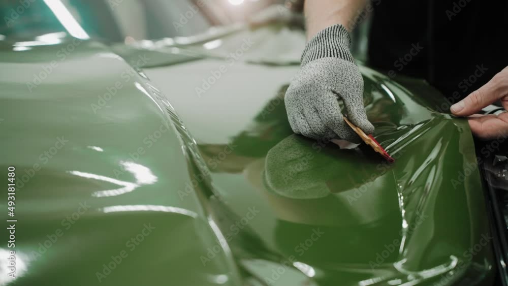 Process of vinyl wrapping a car hood in dark green color using plastic cards. Process of vinyl