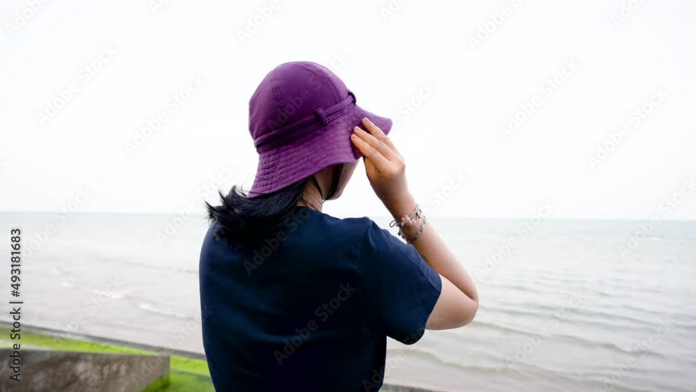 4K 25fps Slow Motion, Asian woman with short hair, wearing a favorite hat, sitting in the view, taking in the good atmosphere by the sea, with peace of mind. 4K 25fps Slow Motion, Asian woman with short hair, wearing a favorite hat, sitting in the view, taking in the good atmosphere by the sea, with peace of mind.