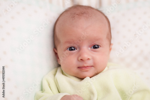 Adorable newborn baby. Newborn child relaxing in bed and smiling. Happy newborn infant baby