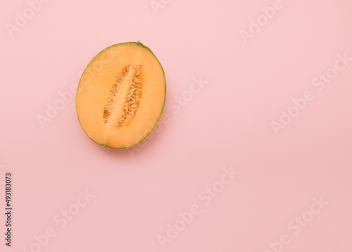 Yellow melon cut in half on pink background. Minimal summer food concept. Flat lay with copy space