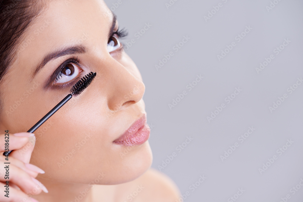 Accentuating her natural beauty. Studio portrait of an attractive young woman applying mascara to her eyelashes.