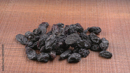 black raisins in a bowl on a wooden table. black raisins in a spoon