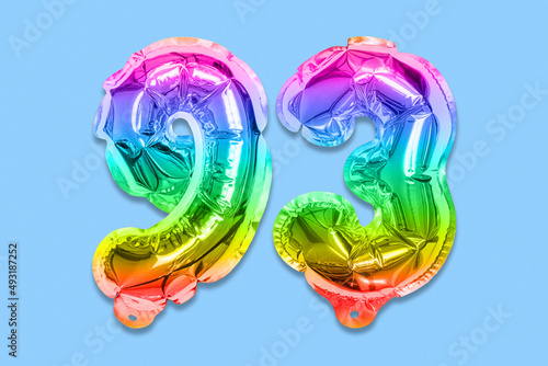 Rainbow foil balloon number, digit ninety three on a blue background. Birthday greeting card with inscription 93. Top view. Numerical digit. Celebration event, template.