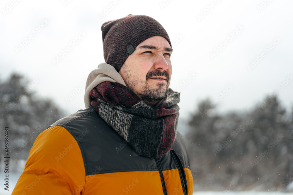 Young man in warm coat standing in snowy winter forest Young man in warm coat standing in snowy winter forest