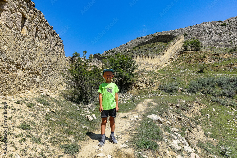 A boy against the background of the Gunib fortress. A protective wall. Russia, Dagestan. June 2021