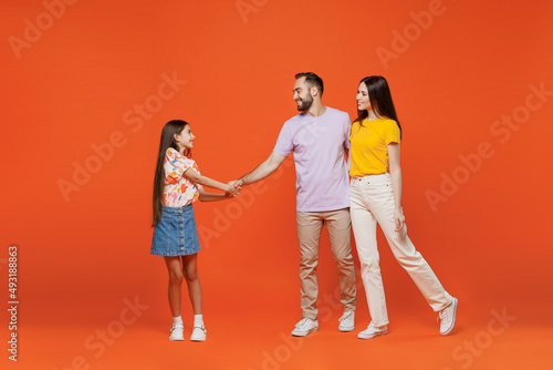 Принти на полотні Full body young smiling happy parents mom dad with child kid daughter teen girl in basic t-shirts hold hands ask to go with her isolated on yellow background