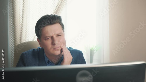 man having toothache while sitting at computer